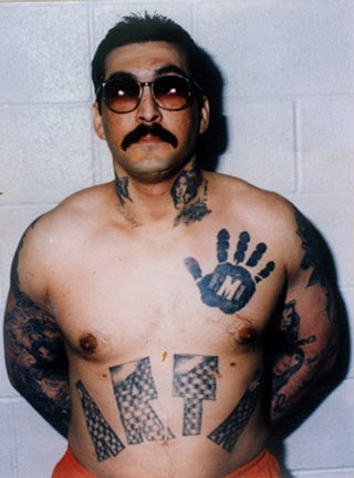 René “Boxer” Hénriquez, originalmente miembro de la pandilla Artesia-13 fue elegido para ser “carnal” de la Mafia Mexicana en los años 80. En su pecho luce el tatuaje de una mano negra reservado solo para los que alcanzan ese estatus.