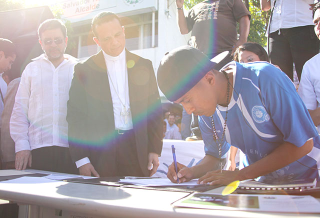 Un pandillero firma un acuerdo de paz entre pandillas en Ilopango bajo la mirada de Fabio Colindres y David Munguía Payés. 22 de enero 2013. Foto El Faro